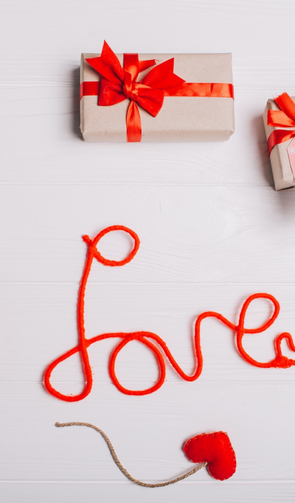 Надпись любовь красными нитями на сером фоне с сердечками и подарками