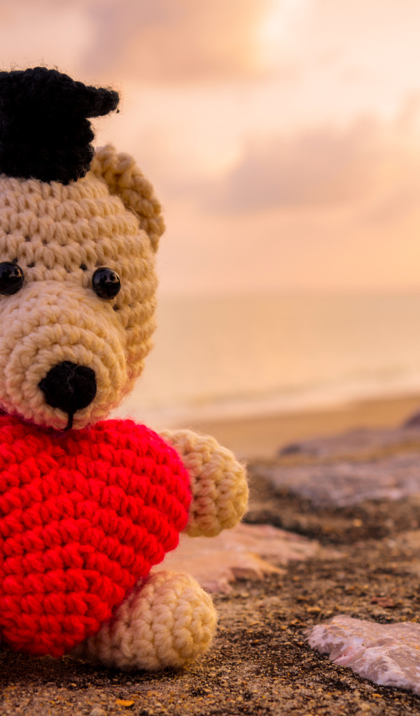 Toy bear with a red heart against the sky