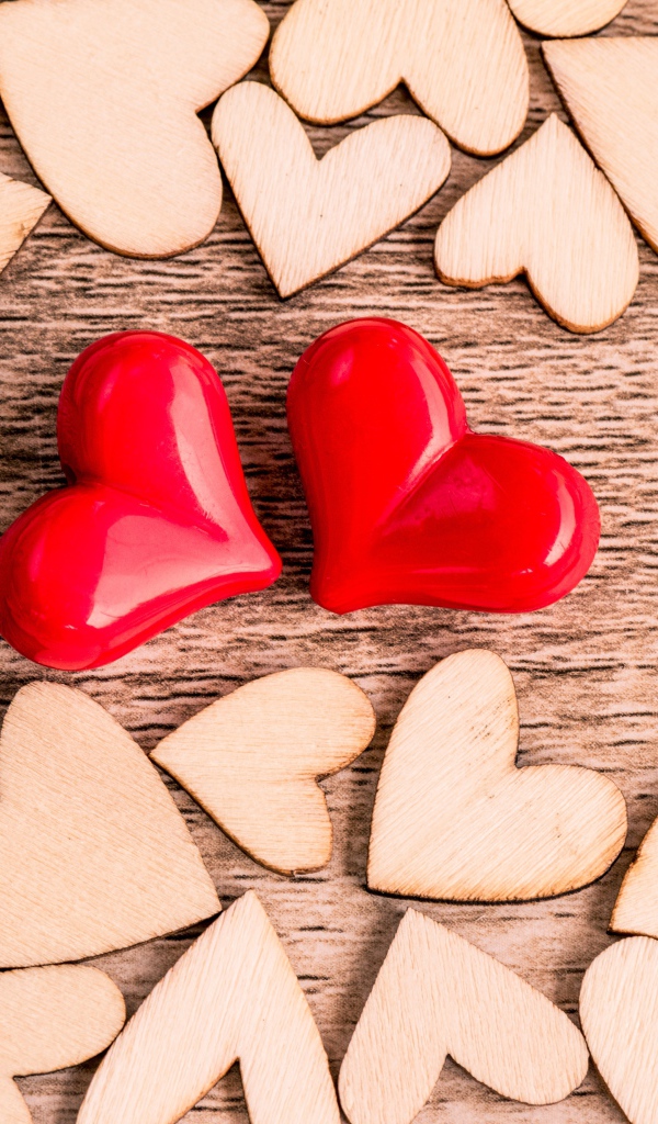 Два красных сердечка на столе с деревянными сердечками