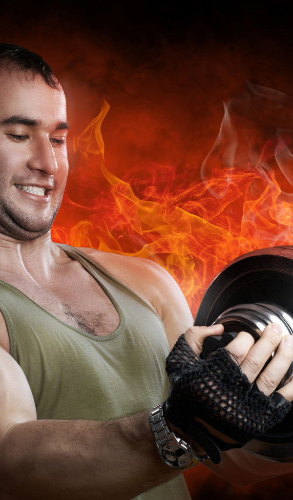Мужчина спортсмен держит в руках гантелю на фоне огня