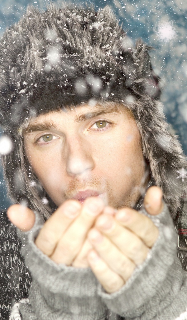 Молодой парень в теплой шапке мерзнет зимой