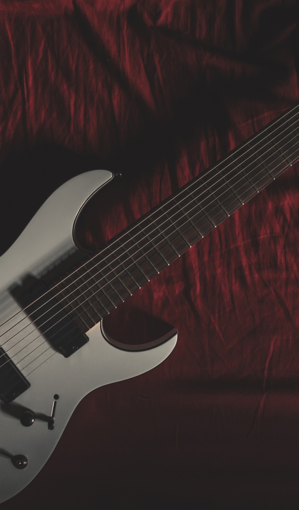 Гитара лежит на красном покрывале