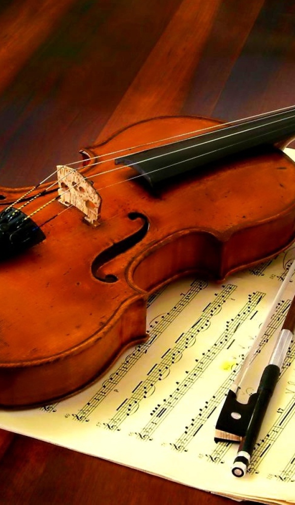 Скрипка со смычком лежат на нотной тетради
