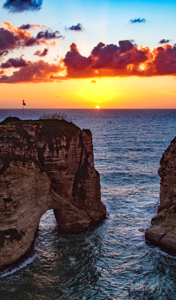 Арка скала в море на закате солнца