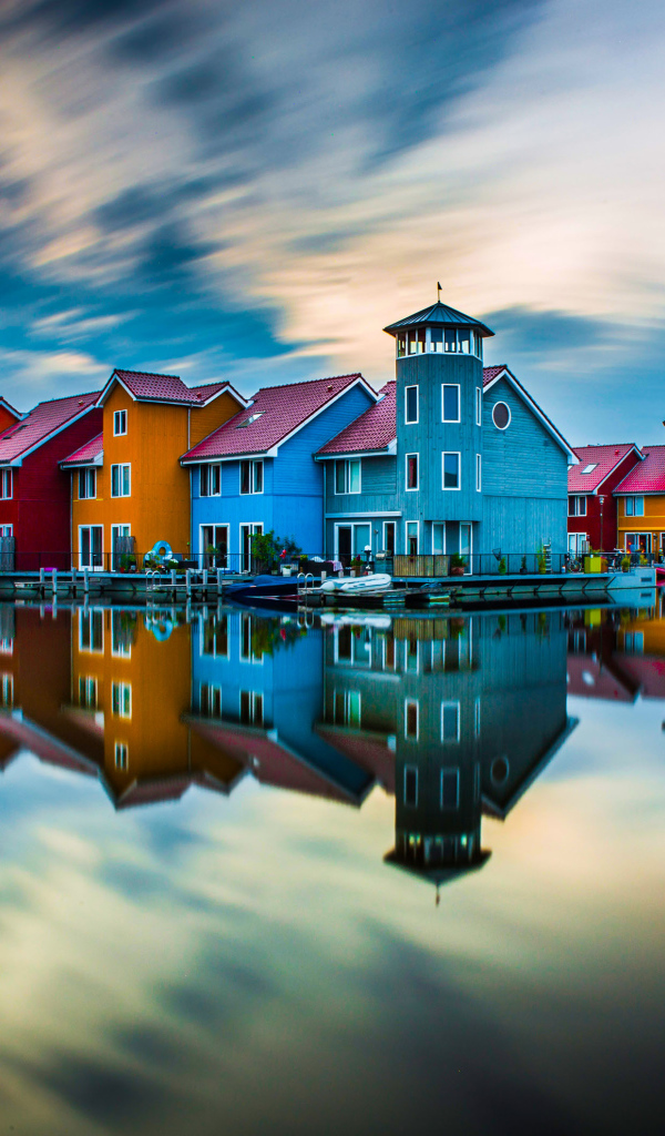 Красивые разноцветные дома отражаются в воде под красивым небом