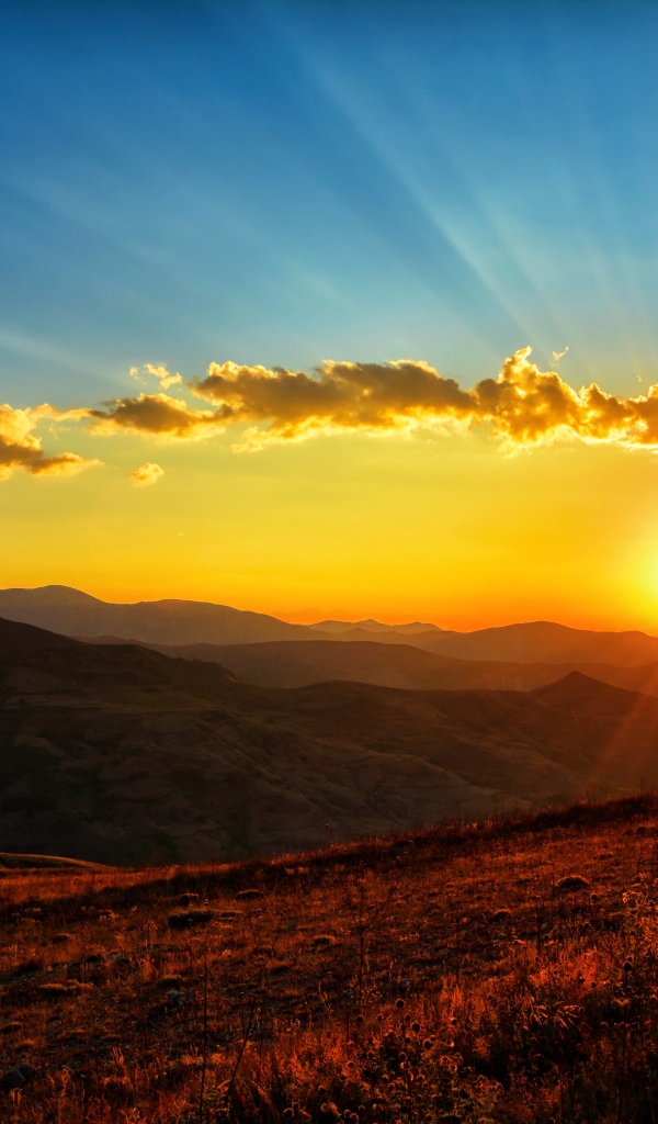 Красивый рассвет в небе над зелеными холмами