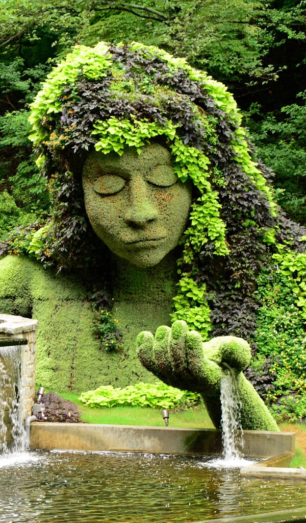 Красивый водопад в парке со скульптурой 