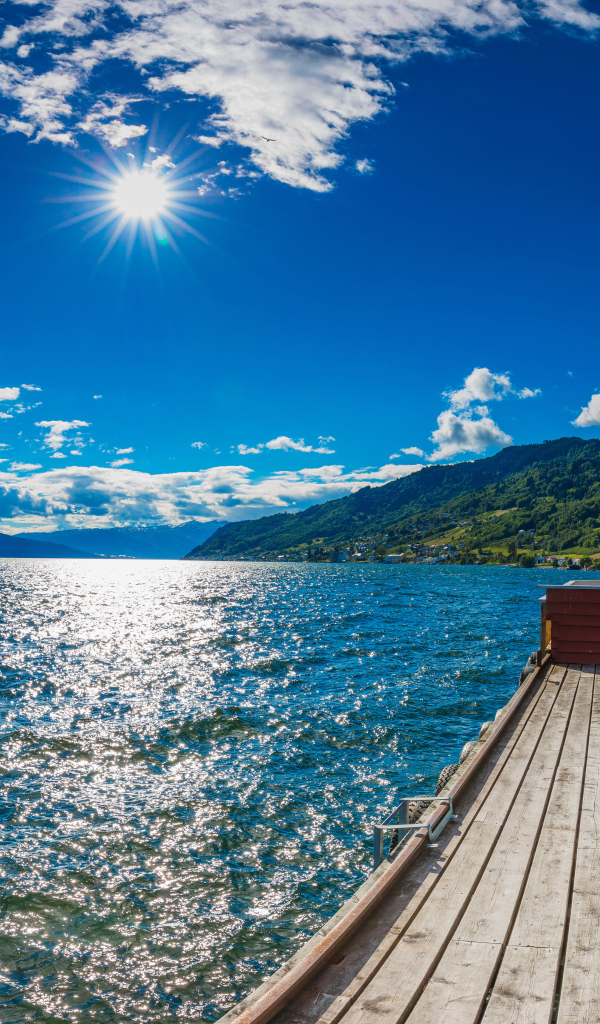 Яркое солнце в голубом небе над водой, Исландия