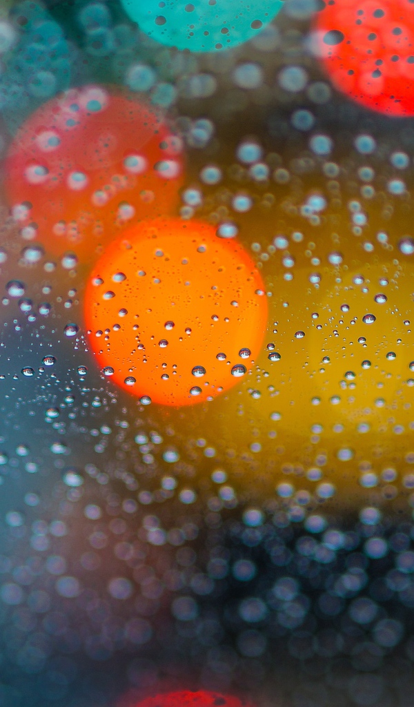 Капли дождя на стекле с разноцветными бликами