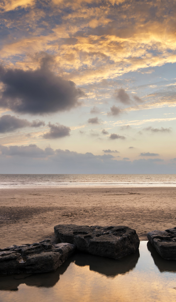 Большие камни в воде на песке под красивым небом