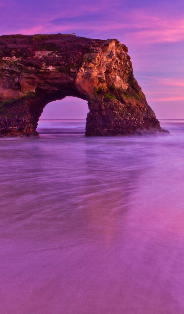 Гора с аркой в океане на фоне красивого неба