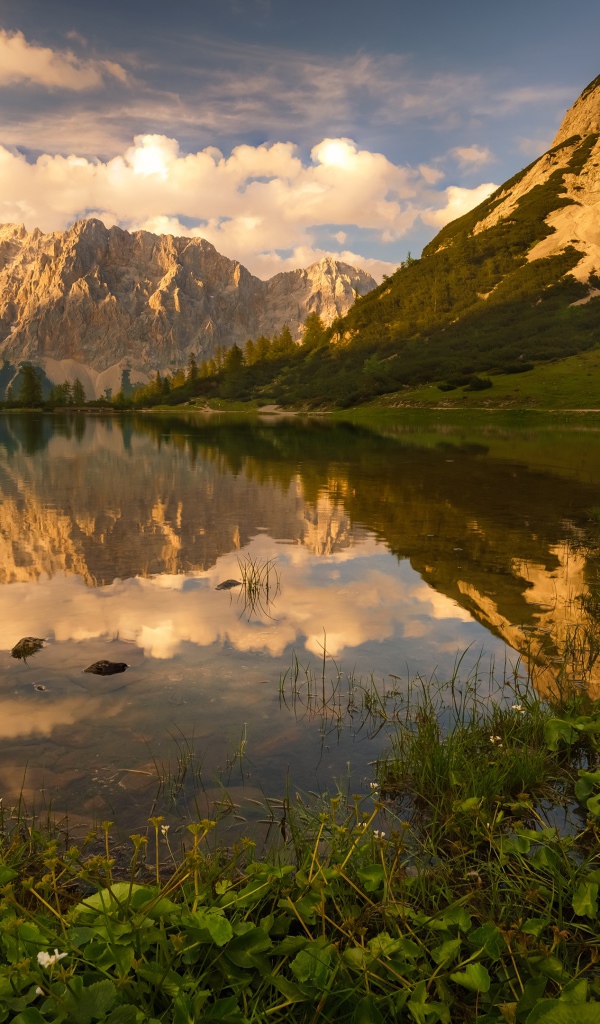 Горы в лучах солнца под красивым небом отражаются в воде