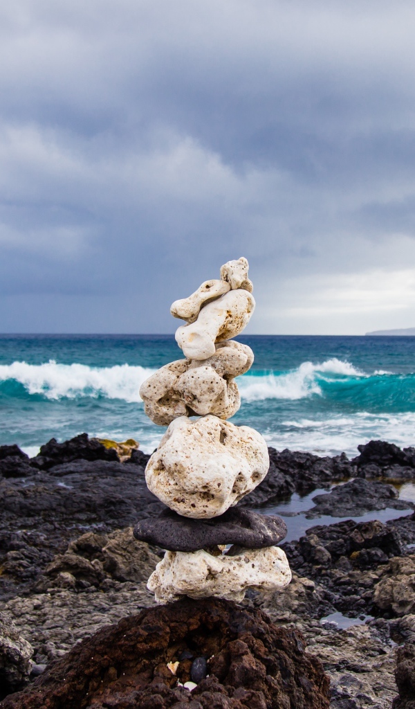 Пирамида из камней у моря на фоне пасмурного неба