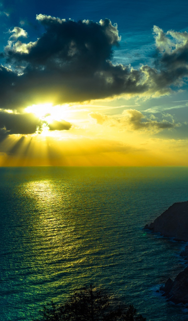 Лучи яркого солнца пробиваются сквозь облака над морем
