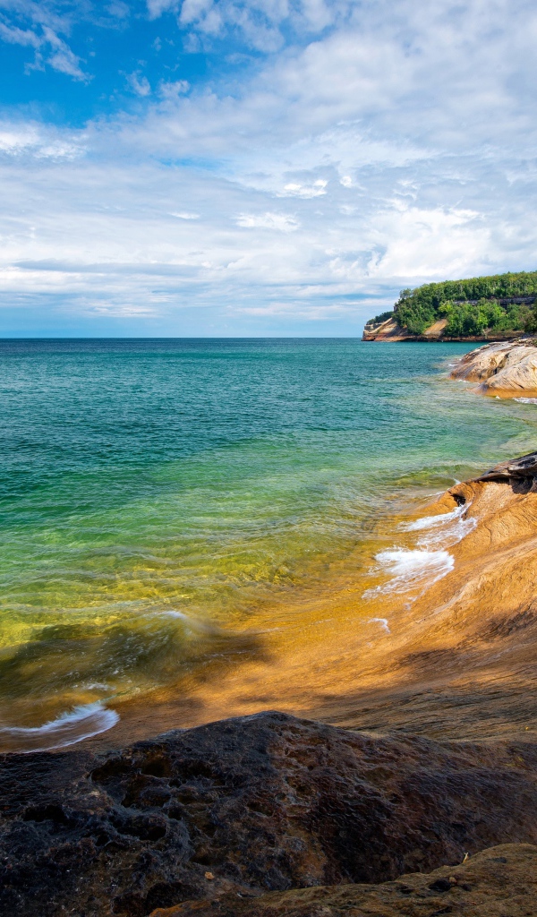 Скалистый берег у голубой воды моря на фоне неба