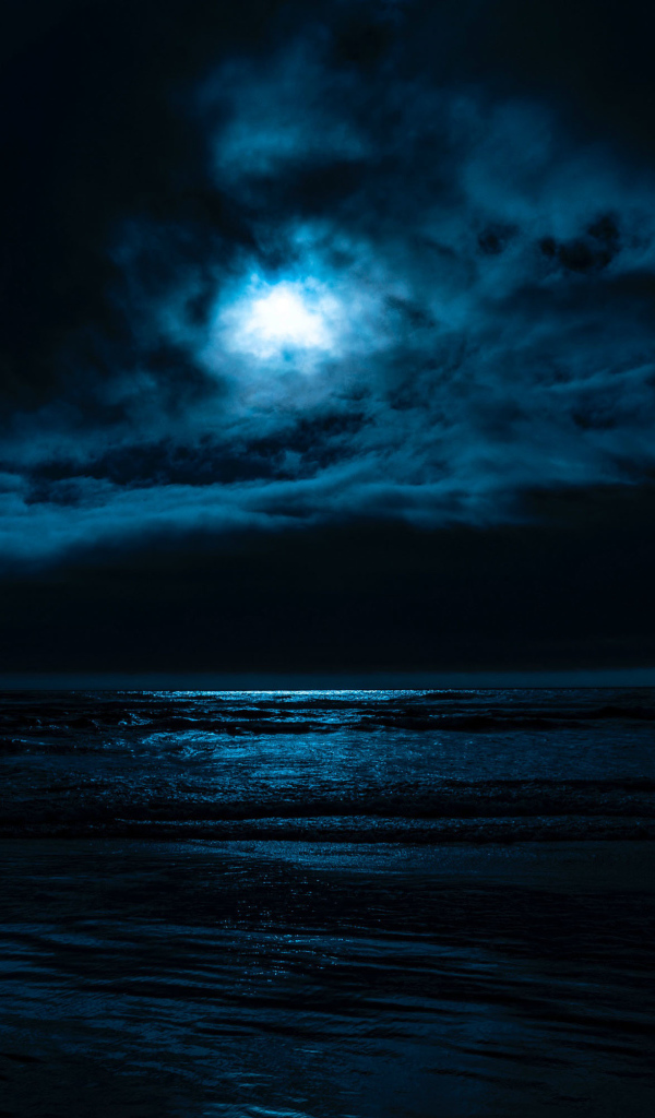 Луна в облачном небе над морем ночью