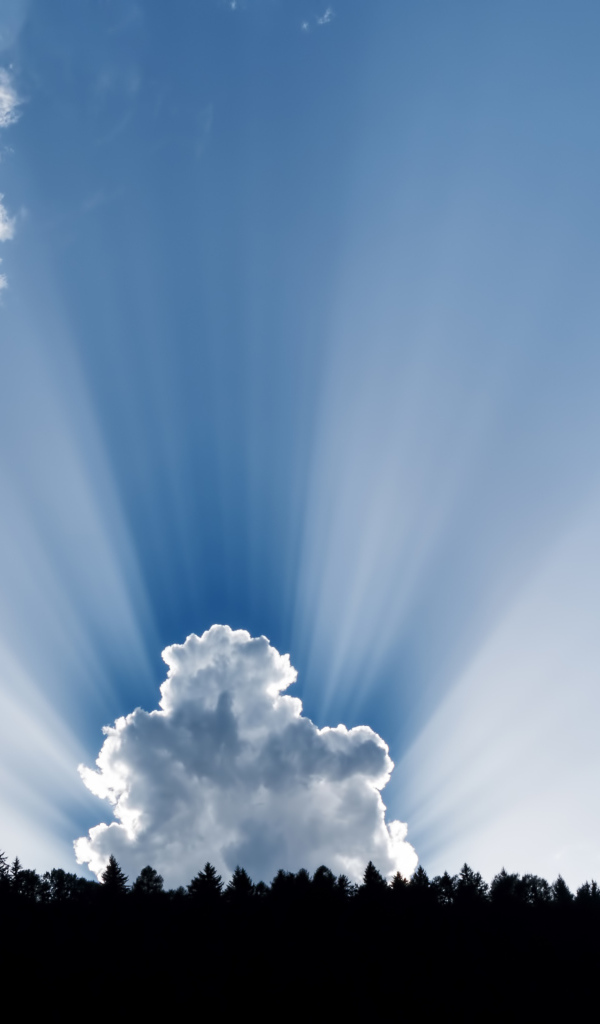 Лучи солнца пробиваются сквозь белые облака в голубом небе 