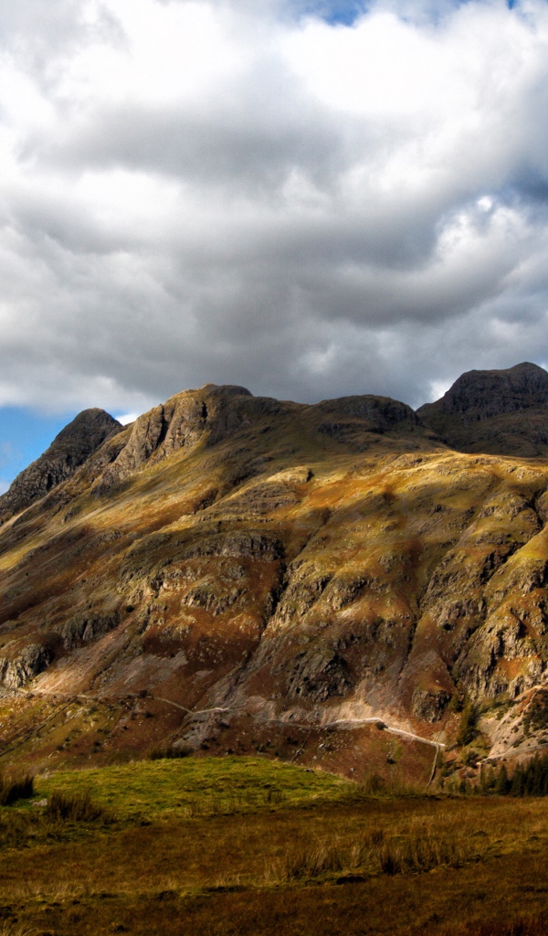 Белые пушистые облака над горой 