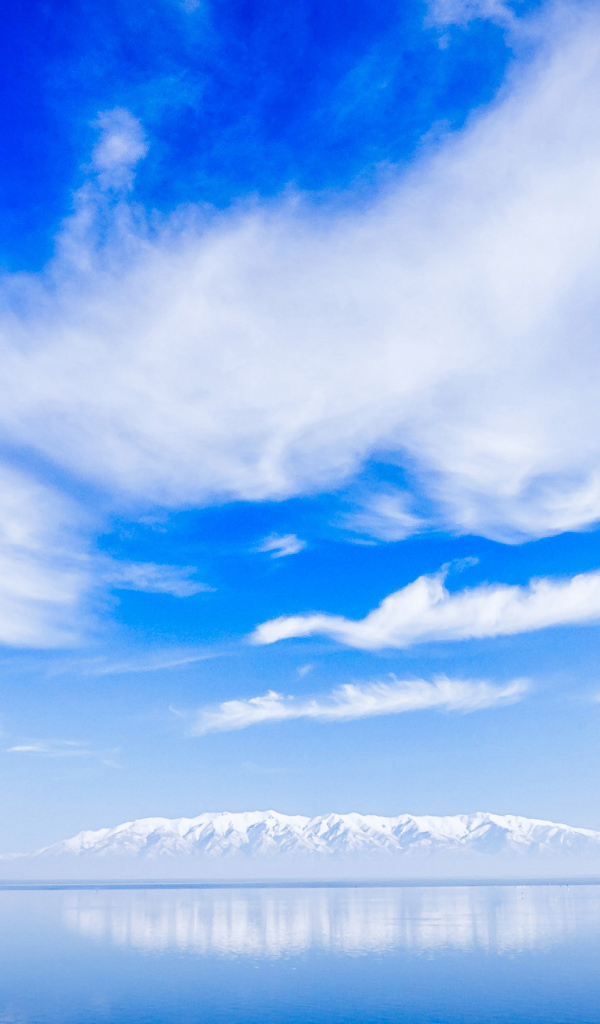 Красивые белые облака над водой около заснеженных гор