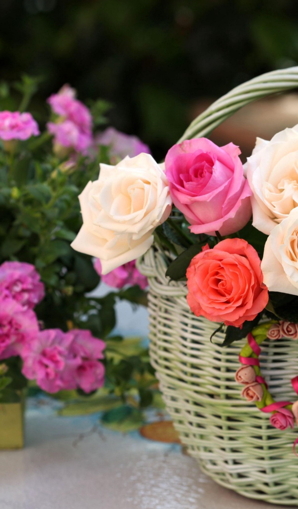 Букет нежных роз в корзине на столе с цветами