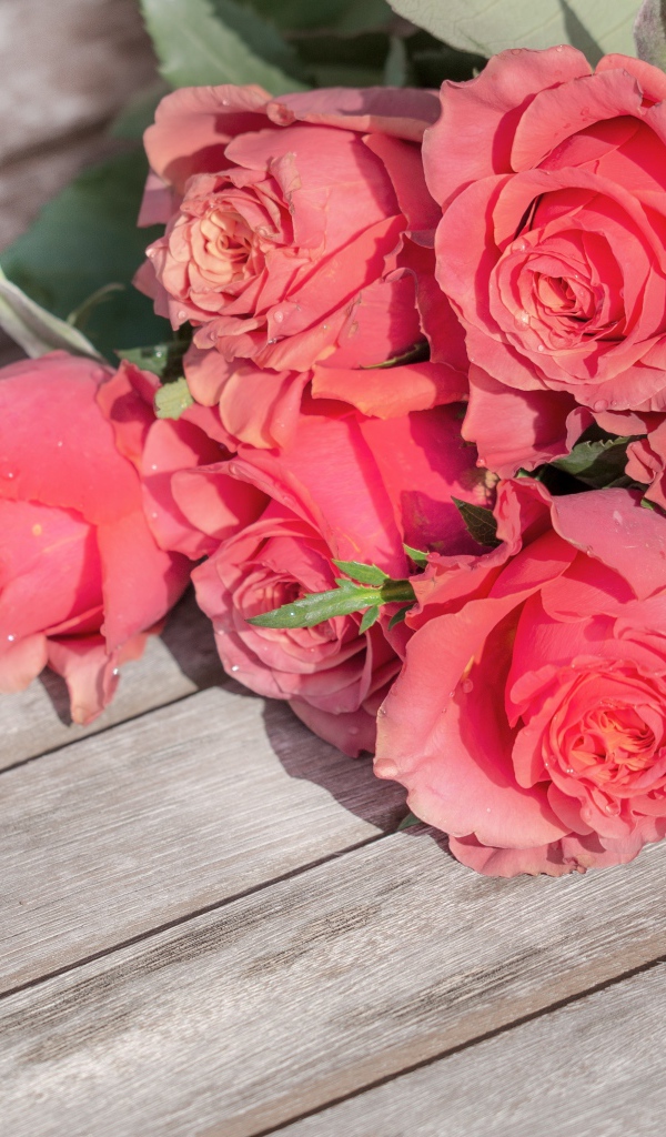 Букет розовых роз лежит на деревянной поверхности