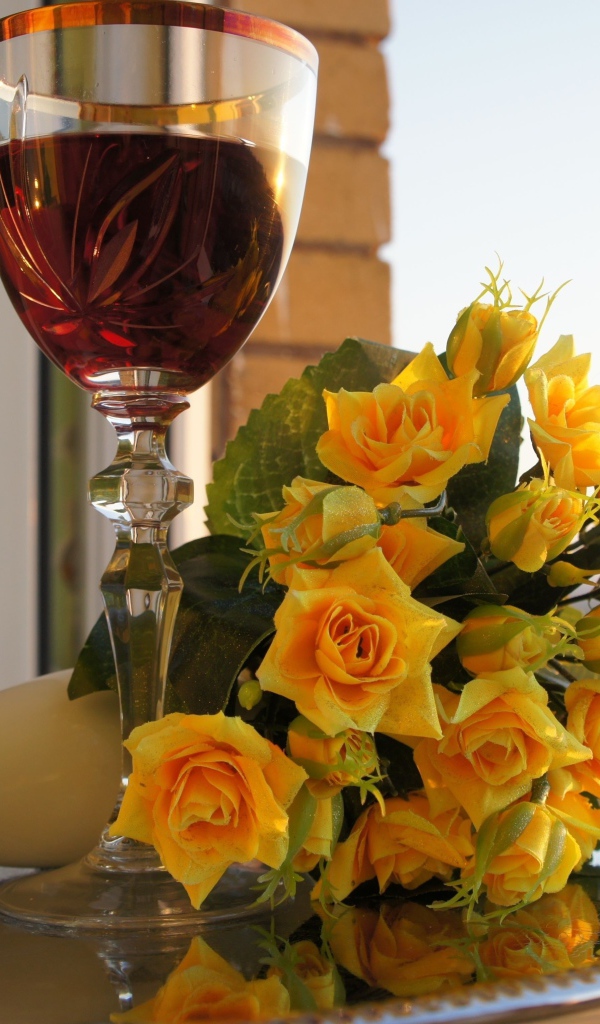 Букет желтых роз на столе с бокалом вина