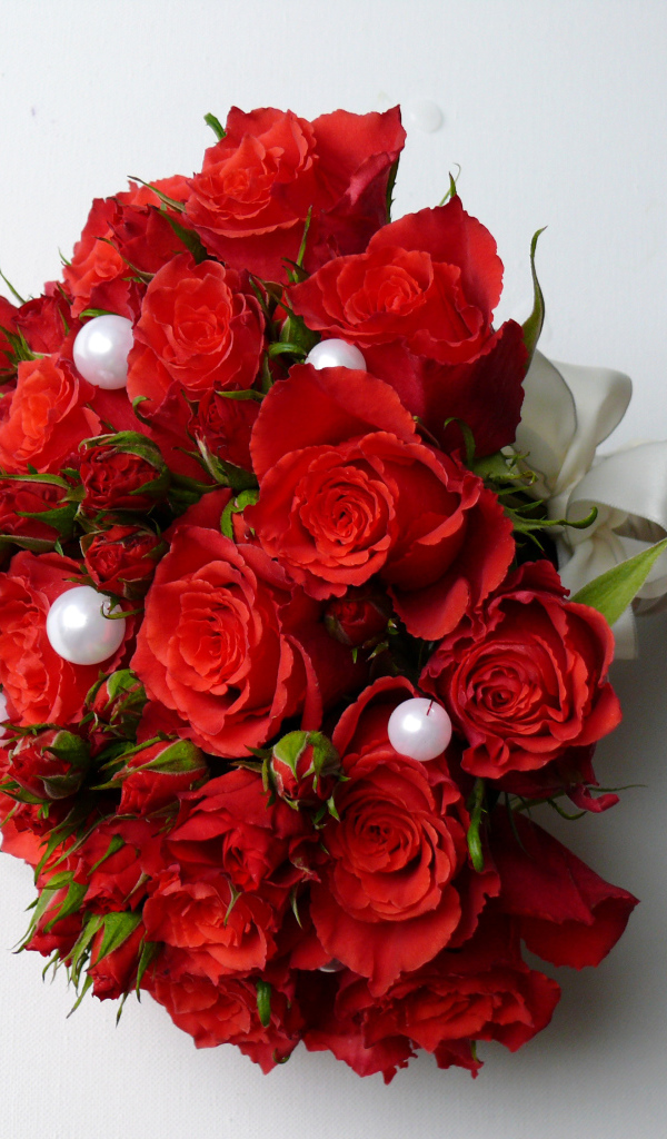 Красивый букет красных роз с жемчужными бусинами на сером фоне
