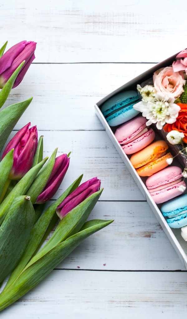 Букет сиреневых тюльпанов на столе с коробкой с макарунами