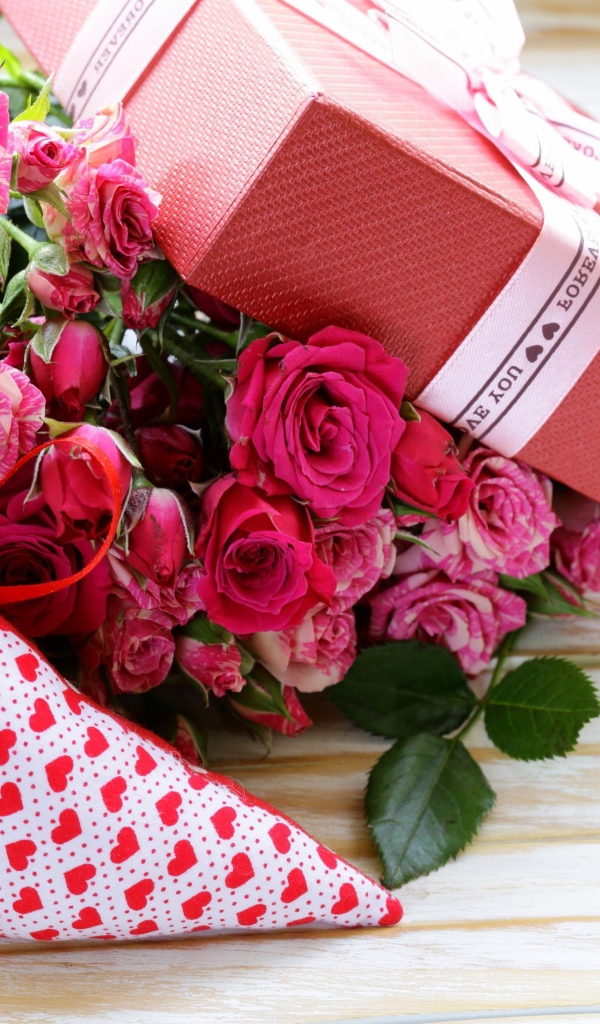 Букет розовых роз с подарком и сердечком на столе