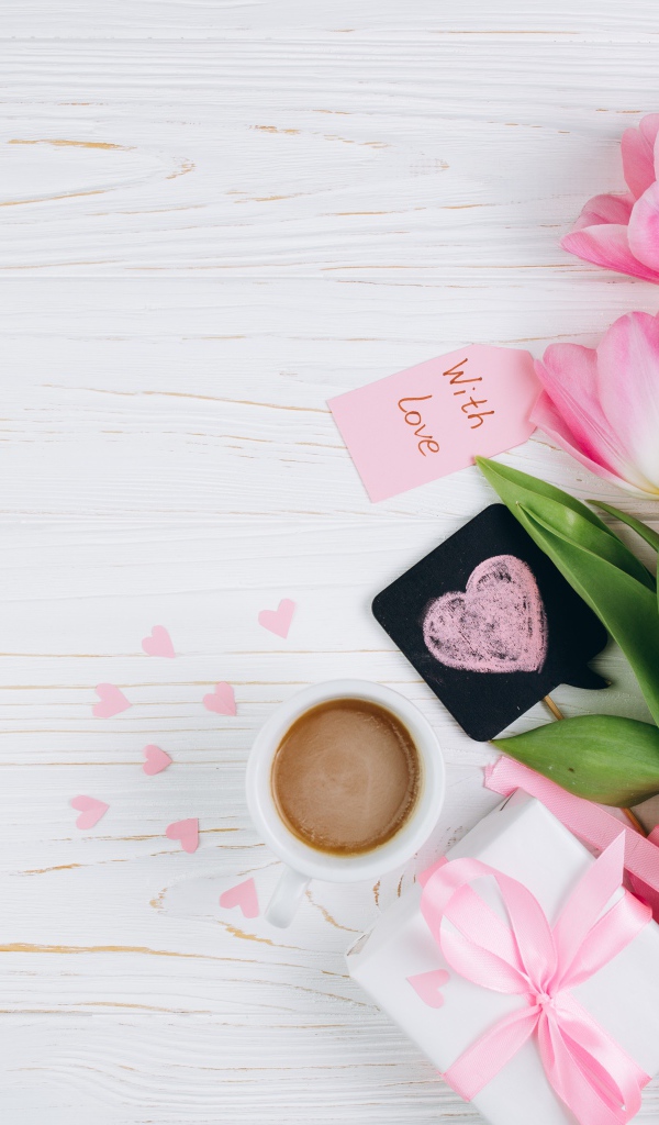 Букет розовых тюльпанов на столе с чашкой кофе и подарком 