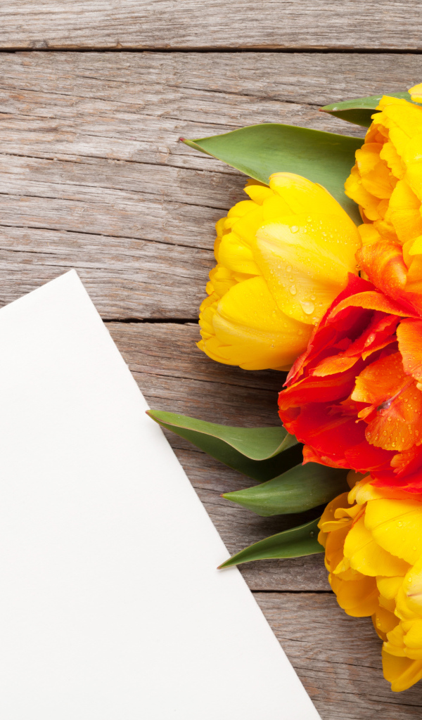 Букет желтых тюльпанов на столе с листом бумаги