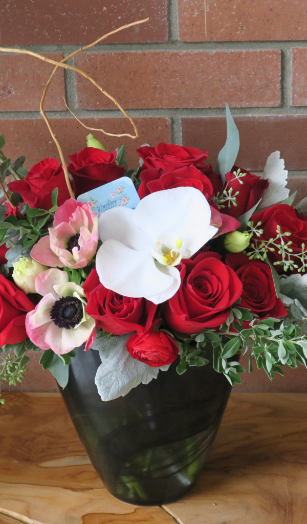 Букет с цветами анемоны, розы и орхидеи у стены 