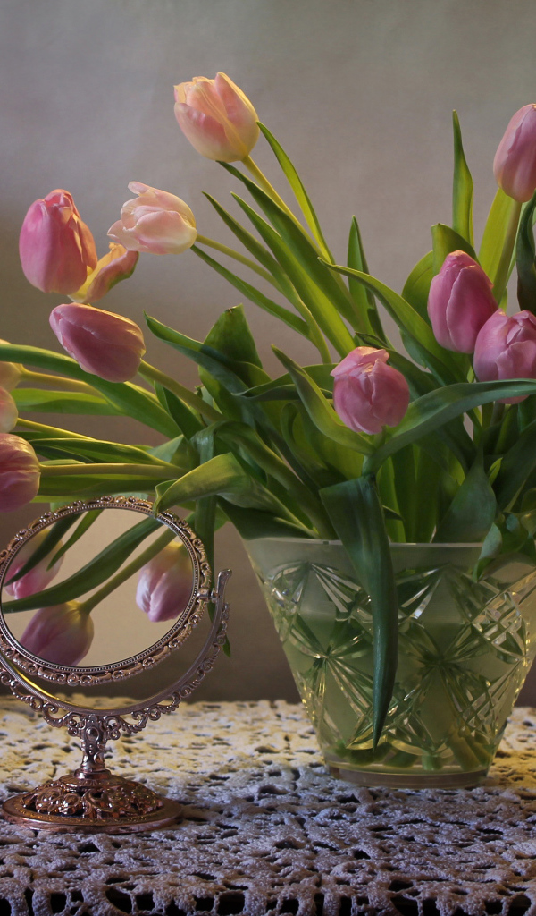 Розовые тюльпаны в стеклянной вазе на столе с зеркалом 