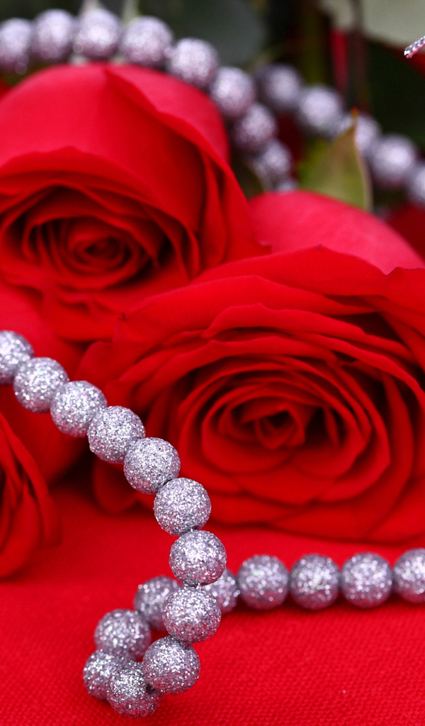 Три красные розы с украшением на красном фоне