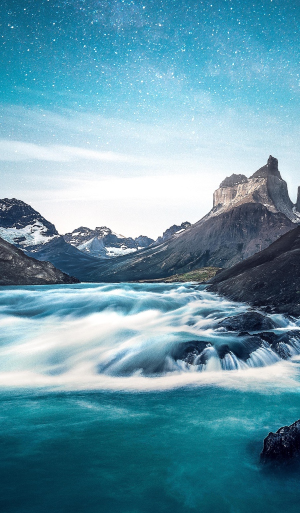 Быстрая вода к реке у гор на фоне голубого неба 