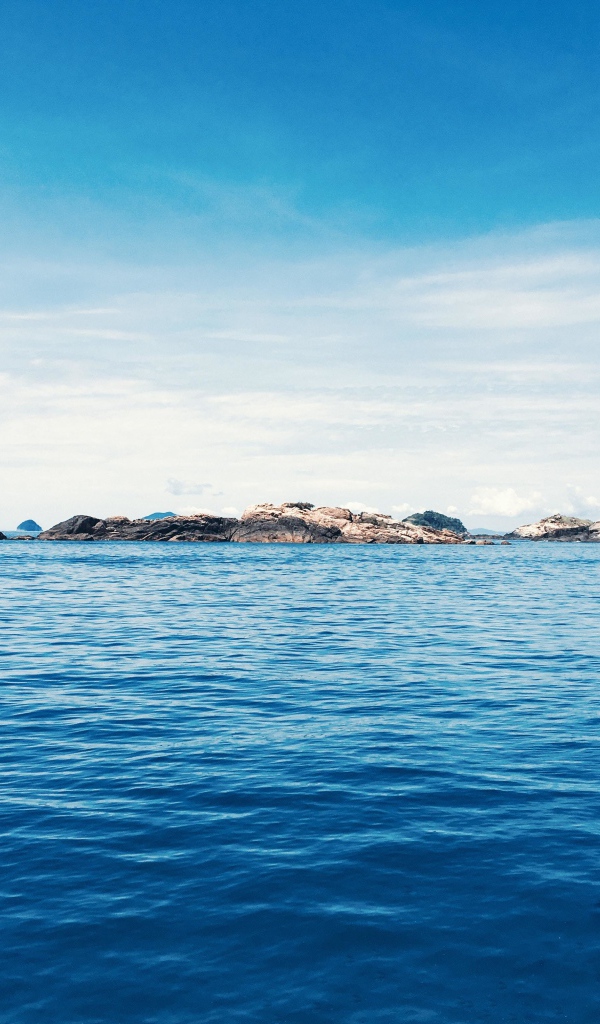 Спокойное синее море со скалами на горизонте