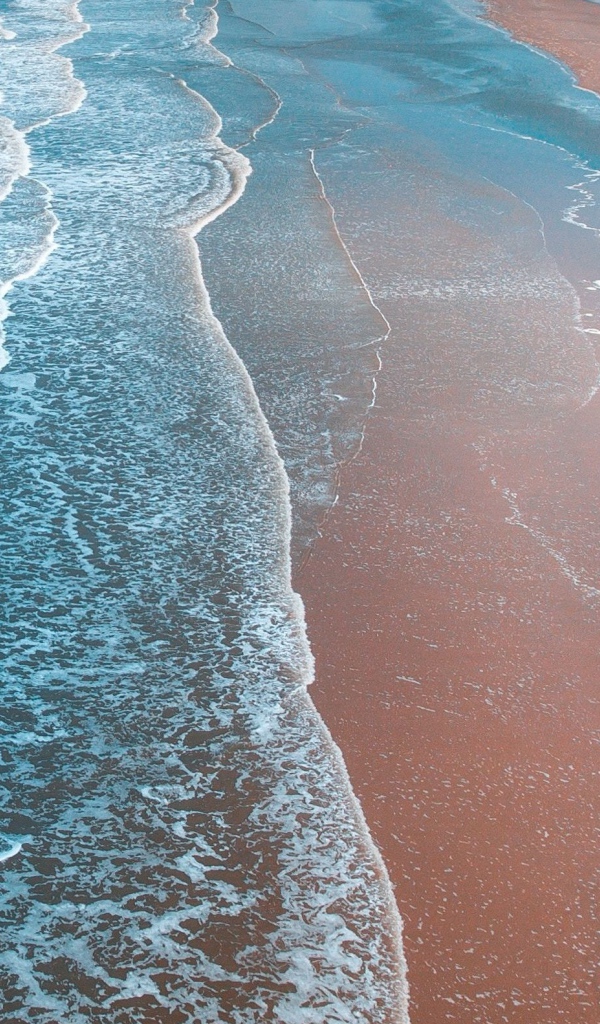 Нежные белые волны омывают песчаный берег океана 