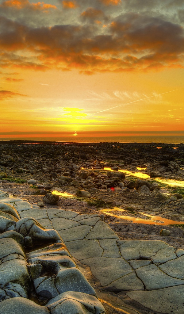 Каменный берег на фоне красивого неба на закате солнца