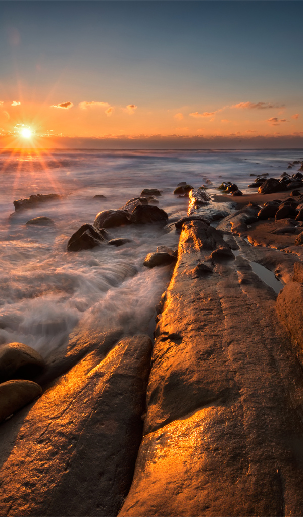 Каменный берег на морском побережье на закате солнца