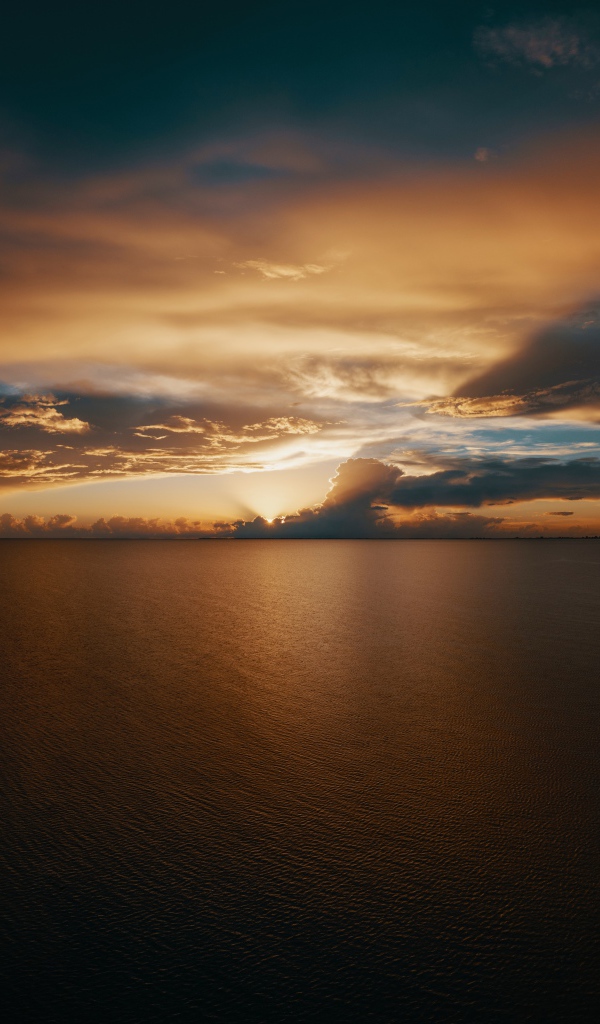 Закат солнца в красивом небе над тихой водой моря