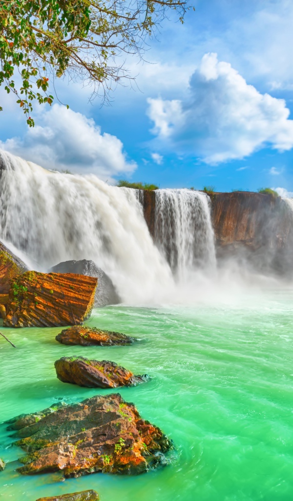 Быстрый водопад стекает со скалы под красивым голубым небом