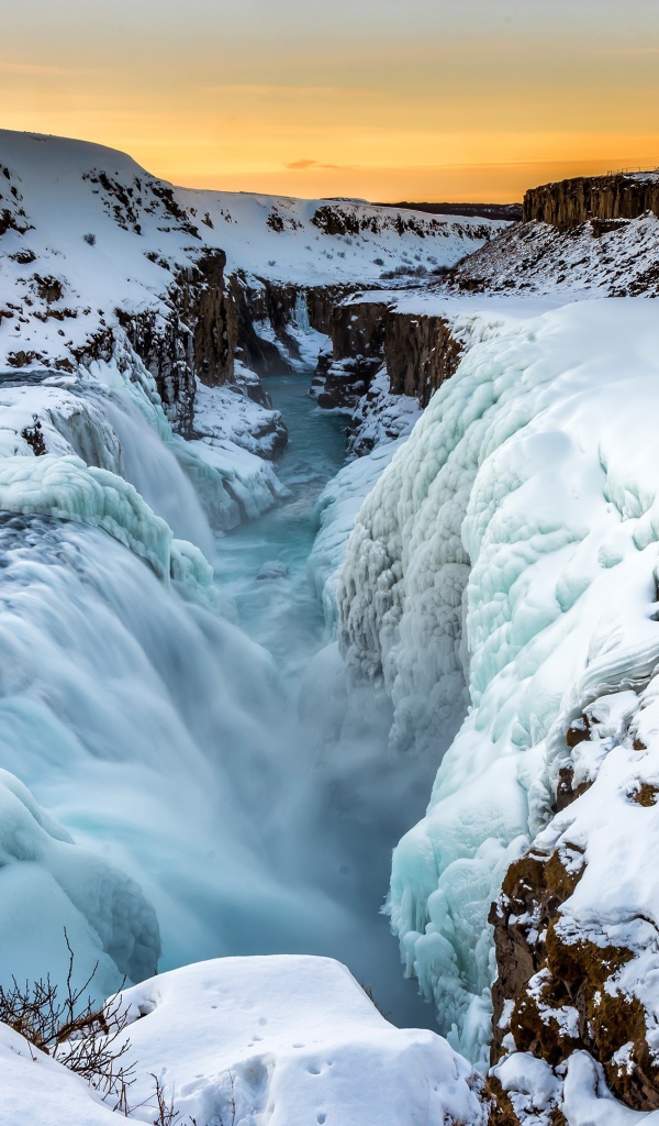 Заледеневший водопад у покрытых снегом берегов, Исландия