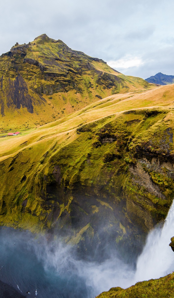 Водопад на фоне покрытых зеленью гор, Исландия