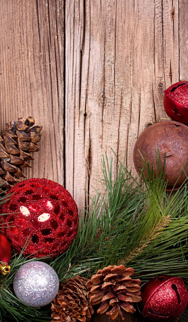 Зеленая еловая ветка с шишками и игрушками на деревянном фоне