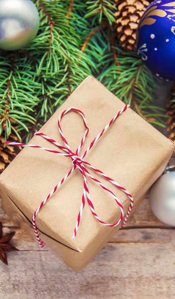 Еловая ветка с игрушками на столе с корицей и подарком на Новый год 