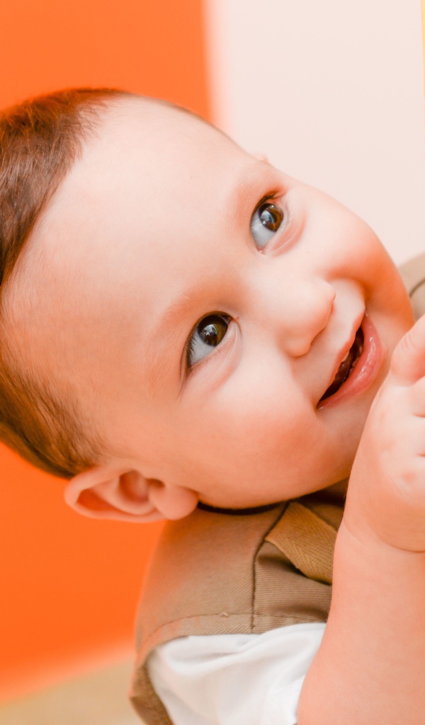 Маленький любопытный мальчик выглядывает из-за стены