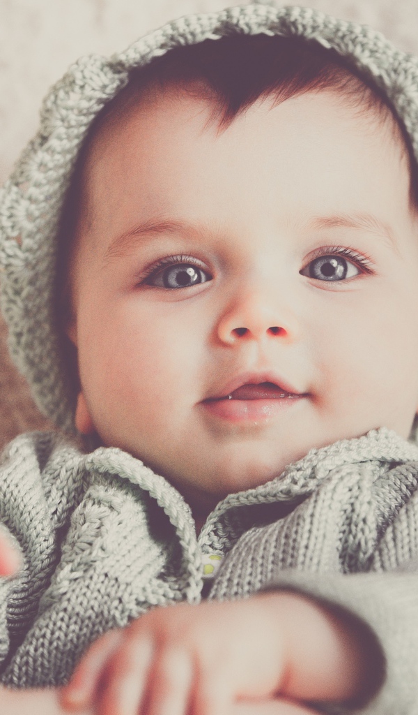 Маленький милый голубоглазый малыш в вязаном костюме