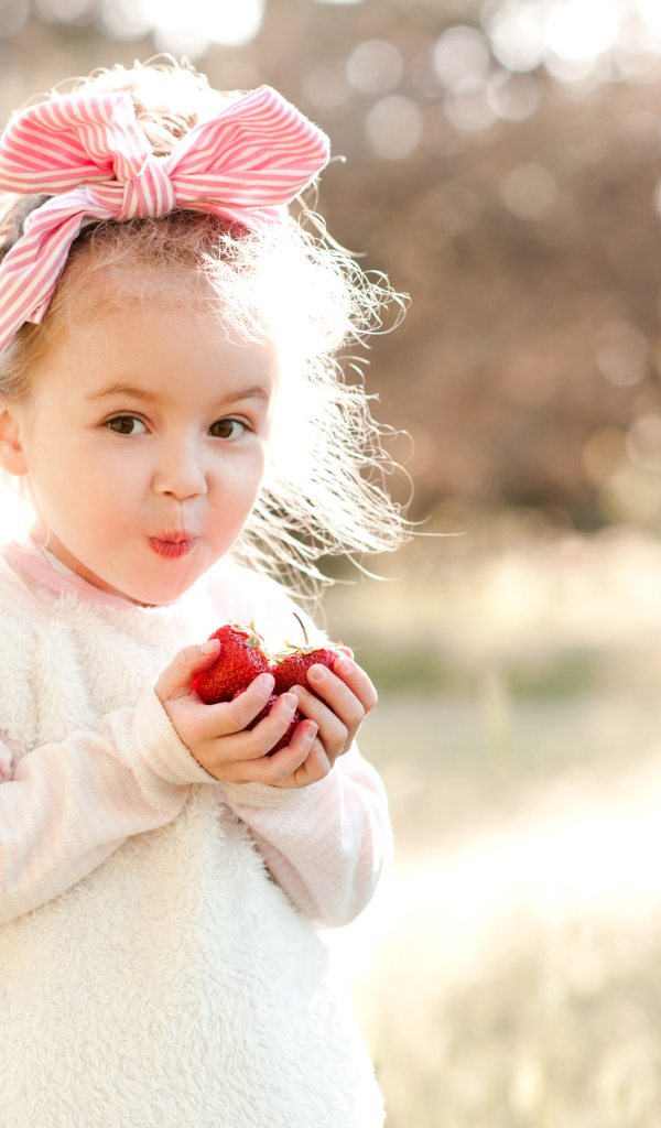 Милая маленькая девочка ест клубнику