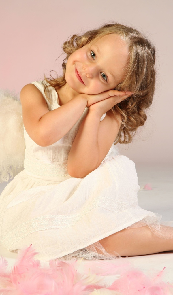 Милая маленькая девочка в белом платье с крыльями ангела