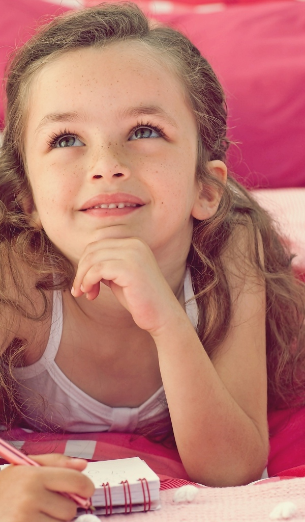 Замечтавшаяся маленькая девочка лежит на кровати